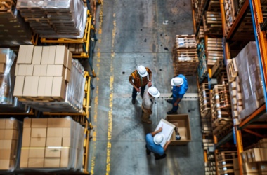 Warehouse workers organizing boxes on high shelves.